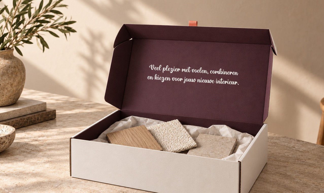Een geopende aubergine box met materiaalstalen en op de binnenflap de tekst: Veel plezier met voelen, combineren en kiezen voor jouw nieuwe interieur.