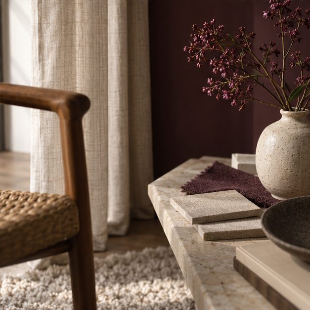 Sfeerbeeld met stenen vaas, droogbloemen en een aubergine wand